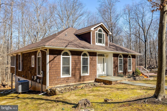 view of front of home featuring a shingled roof, a front lawn, and central AC unit