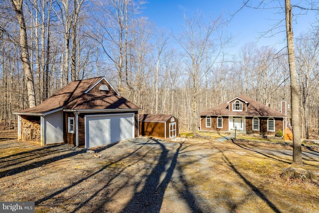 exterior space featuring a garage, an outdoor structure, driveway, and a shed