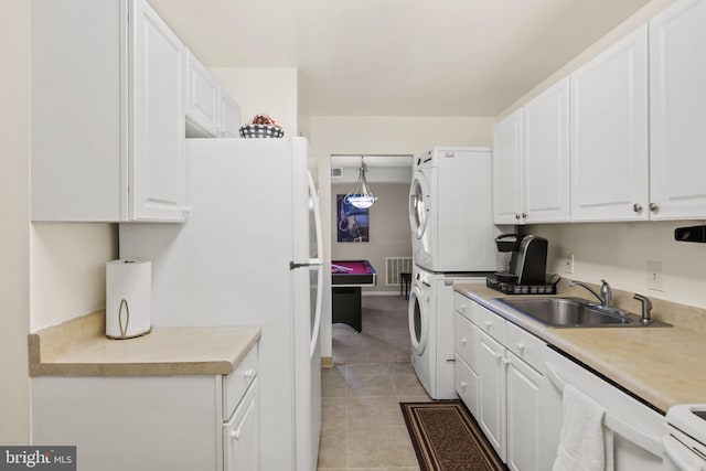 kitchen with sink, white appliances, white cabinets, and stacked washing maching and dryer