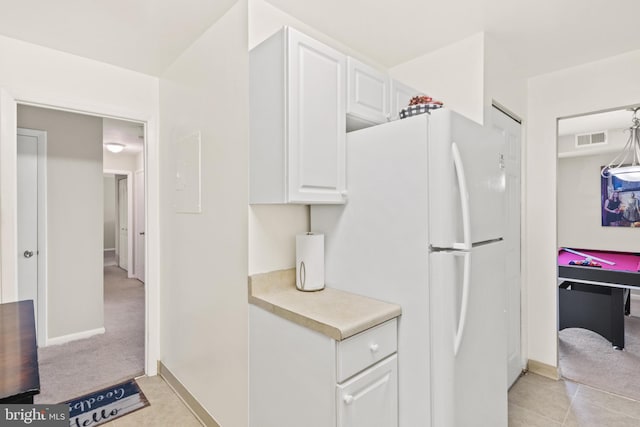 kitchen featuring white cabinetry, decorative light fixtures, light colored carpet, and white fridge