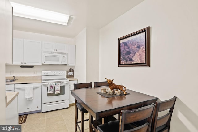 kitchen with white cabinetry, sink, white appliances, and light tile patterned flooring