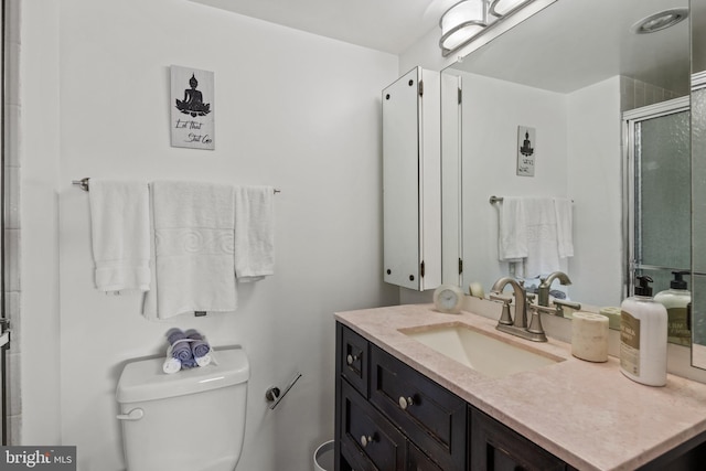 bathroom featuring vanity, toilet, and a shower with shower door