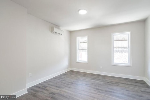 empty room featuring a wall unit AC and dark hardwood / wood-style floors