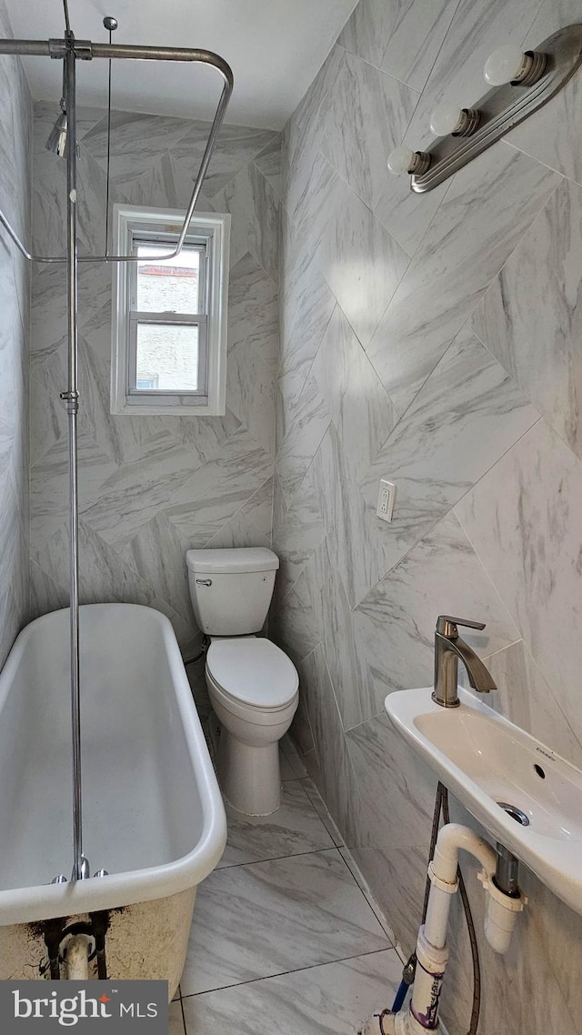 bathroom featuring tile walls, a tub to relax in, sink, and toilet