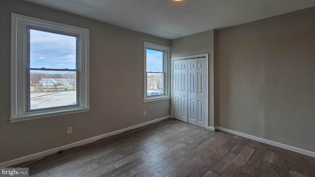 unfurnished bedroom featuring multiple windows, hardwood / wood-style flooring, and a closet