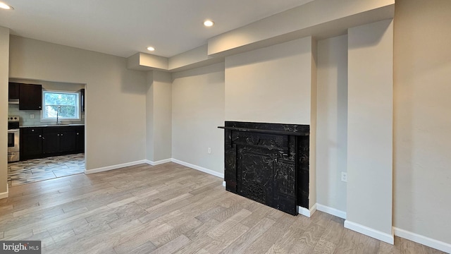 unfurnished living room with sink and light wood-type flooring