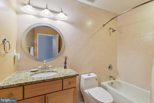 full bathroom with toilet, tile walls, vanity, tiled shower / bath combo, and backsplash