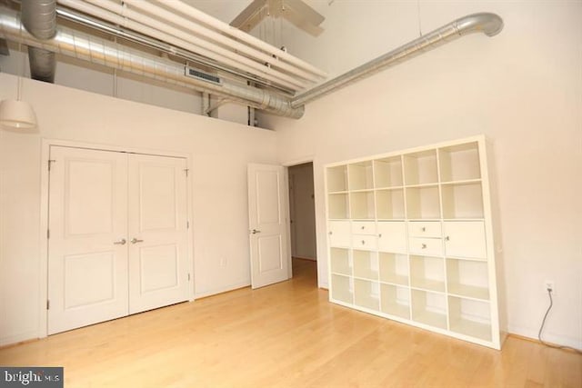 unfurnished bedroom featuring hardwood / wood-style floors, a towering ceiling, a closet, and ceiling fan