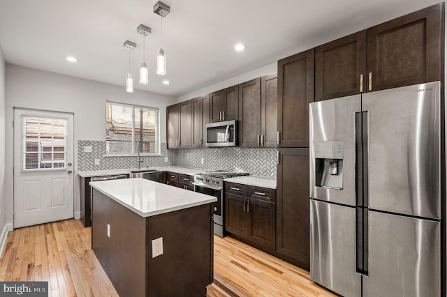 kitchen with sink, tasteful backsplash, hanging light fixtures, a kitchen island, and stainless steel appliances