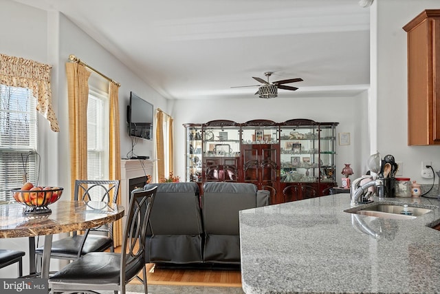 living area featuring light wood-style flooring, a fireplace, and ceiling fan