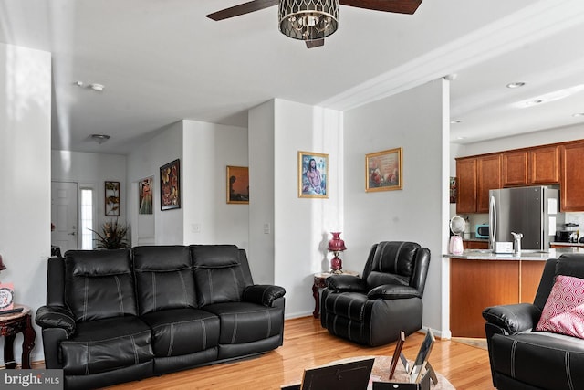 living room featuring baseboards, light wood-type flooring, and ceiling fan