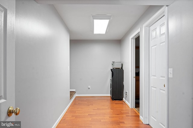 corridor with light wood-type flooring and baseboards