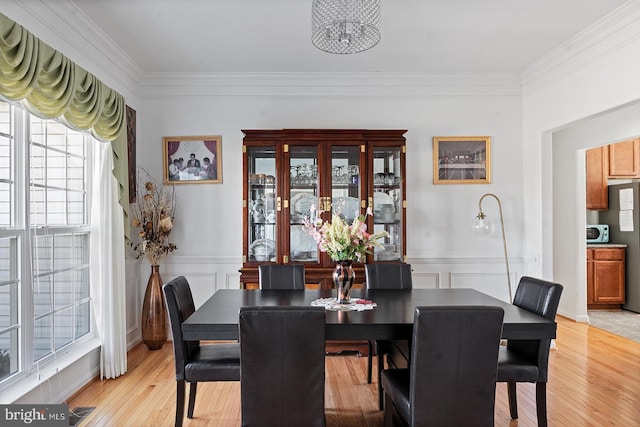 dining room with crown molding, light wood-style flooring, and visible vents