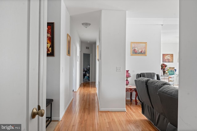 hallway featuring visible vents, light wood-style floors, and baseboards