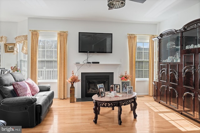 sitting room featuring a wealth of natural light, a fireplace with flush hearth, and light wood-style floors