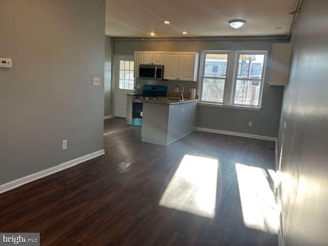 kitchen featuring sink, dark wood-type flooring, white cabinetry, stainless steel appliances, and kitchen peninsula