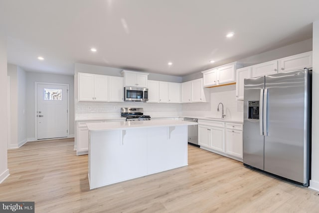 kitchen with white cabinetry, light hardwood / wood-style flooring, stainless steel appliances, and a kitchen island