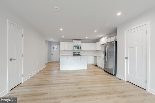 kitchen with white cabinetry, light wood-type flooring, a center island, and appliances with stainless steel finishes