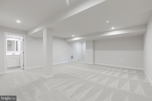 basement with sink and light carpet