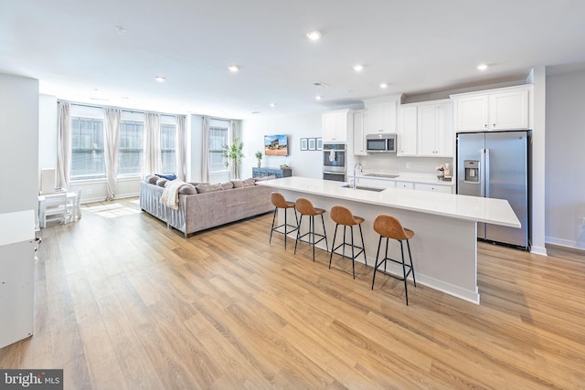 kitchen featuring a center island with sink, a breakfast bar area, appliances with stainless steel finishes, white cabinetry, and a sink