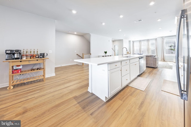 kitchen featuring stainless steel appliances, a sink, visible vents, light wood-style floors, and open floor plan