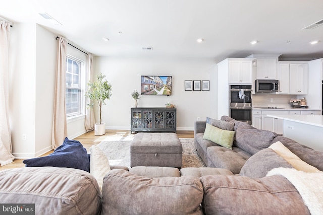 living area featuring light wood-type flooring, visible vents, and recessed lighting