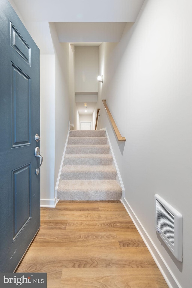 stairs with visible vents, baseboards, and wood finished floors