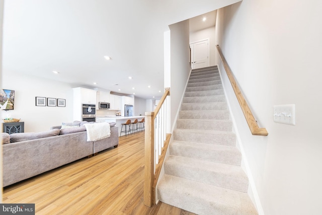 stairs featuring baseboards, wood finished floors, and recessed lighting