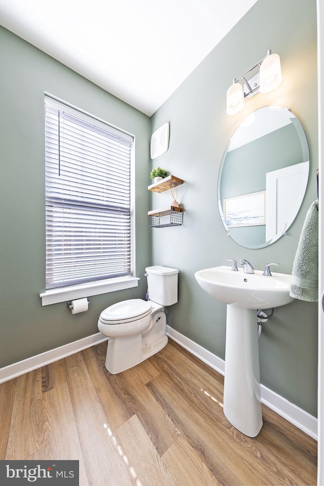 half bath featuring toilet, plenty of natural light, and baseboards