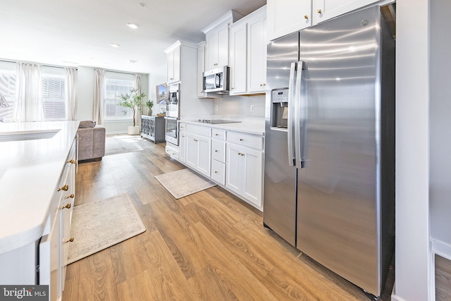 kitchen featuring light wood-type flooring, white cabinetry, appliances with stainless steel finishes, and a sink