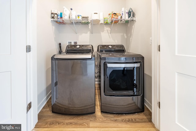 washroom featuring laundry area, independent washer and dryer, wood finished floors, and baseboards