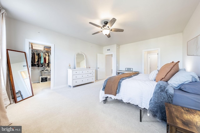 bedroom with visible vents, a ceiling fan, light colored carpet, a walk in closet, and a closet