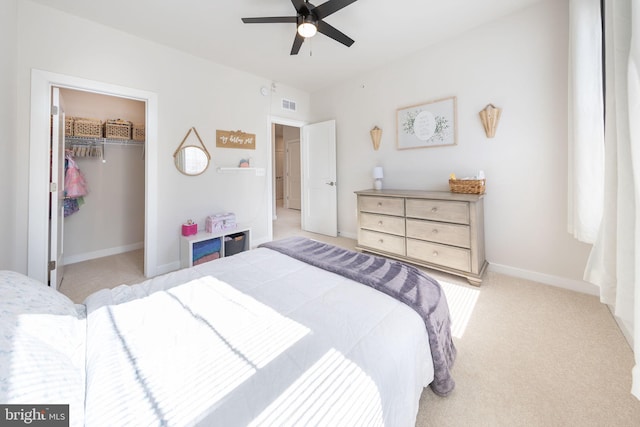 bedroom with a walk in closet, a closet, visible vents, light carpet, and baseboards