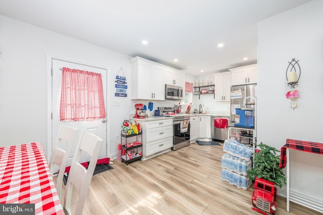 kitchen with white cabinetry, appliances with stainless steel finishes, sink, and light hardwood / wood-style floors