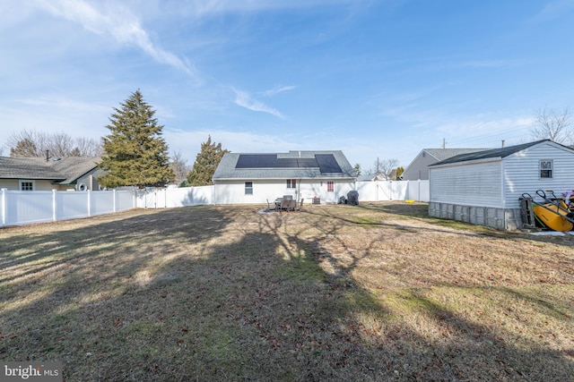 rear view of house featuring a yard and solar panels