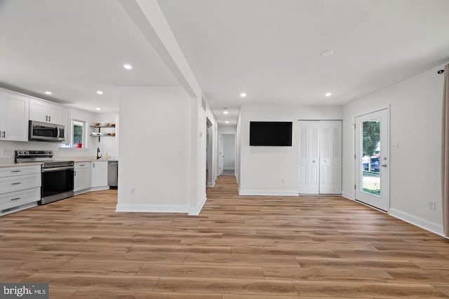 kitchen with stainless steel appliances, sink, light hardwood / wood-style floors, and white cabinets