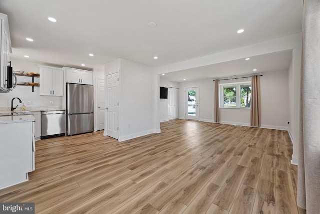 kitchen featuring stainless steel appliances, sink, white cabinets, and light wood-type flooring