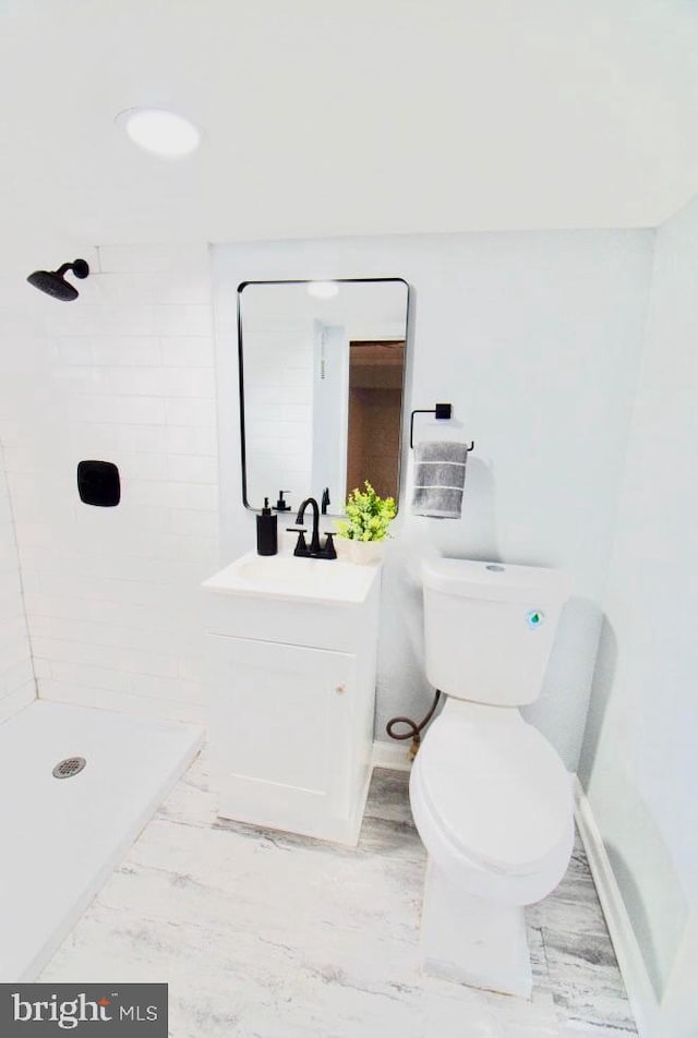 bathroom with toilet, a stall shower, baseboards, and vanity