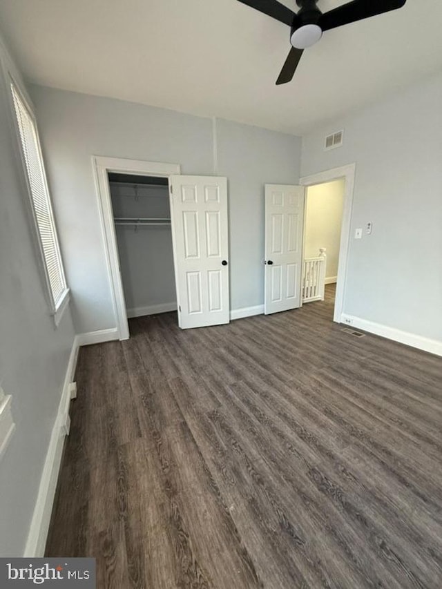 unfurnished bedroom featuring dark wood finished floors, a closet, visible vents, ceiling fan, and baseboards