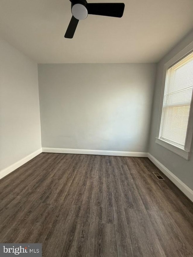 empty room with dark wood-style floors, ceiling fan, and baseboards