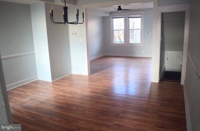 unfurnished dining area featuring ceiling fan with notable chandelier and wood finished floors