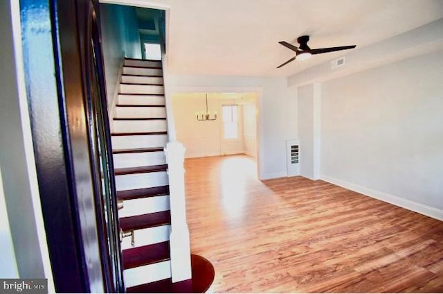 interior space featuring stairs, ceiling fan with notable chandelier, wood finished floors, and baseboards