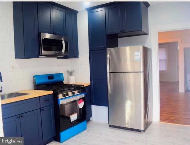 kitchen featuring blue cabinets, a sink, stainless steel appliances, and light countertops