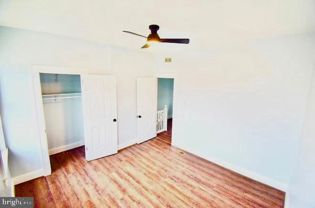 unfurnished bedroom with a closet, wood finished floors, a ceiling fan, and baseboards