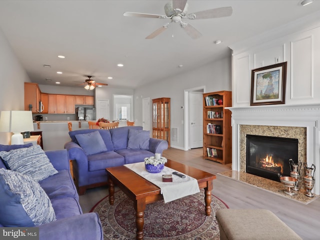 living room with ceiling fan, a fireplace, and light wood-type flooring