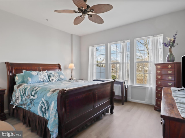 bedroom featuring ceiling fan, multiple windows, and light wood-type flooring