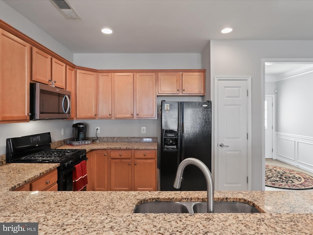 kitchen featuring light stone counters, crown molding, sink, and black appliances