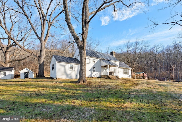 view of side of home with a storage shed and a yard