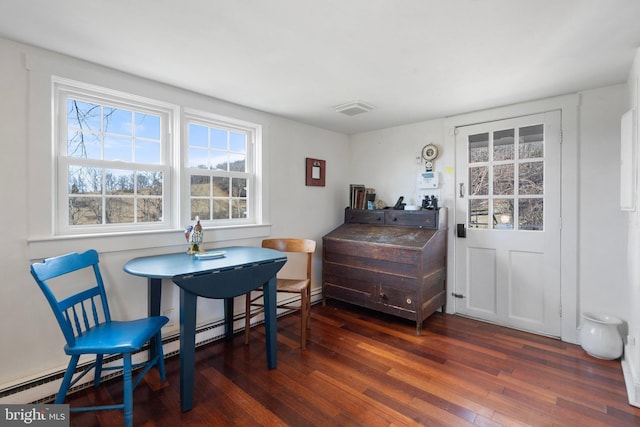 dining space with a baseboard heating unit and dark wood-type flooring