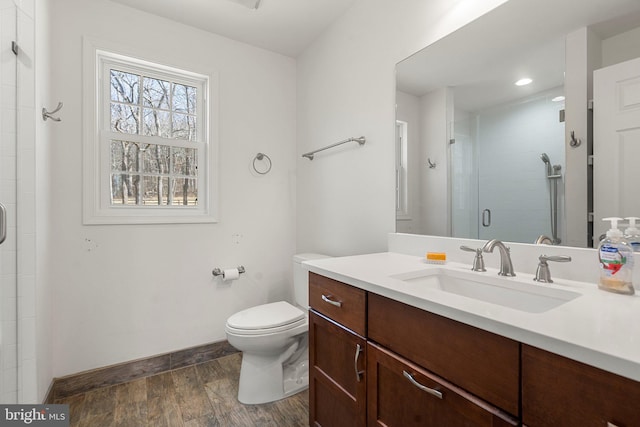 bathroom featuring toilet, vanity, and a shower with shower door